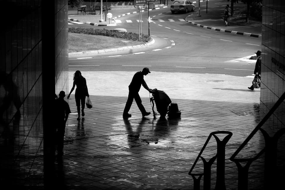 Cleaner mopping a paved outdoor area beside a building