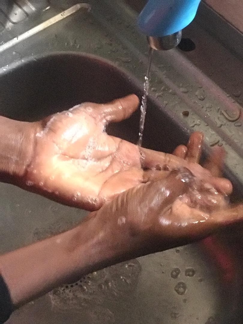 Hands being washed with soap at a sink