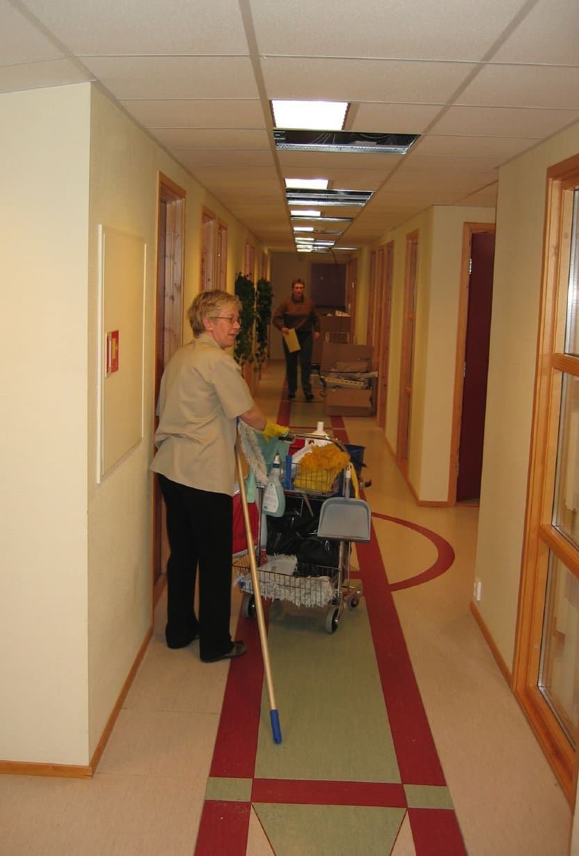 Cleaner working in an office corridor with a mop